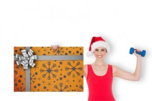 Composite image of festive fit brunette holding gift card and du